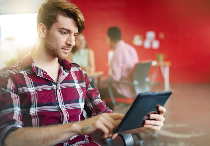 Man in a red shirt typing on a tablet