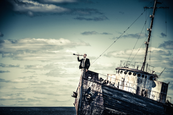 Man in black suit holding a telescope standing on a ship